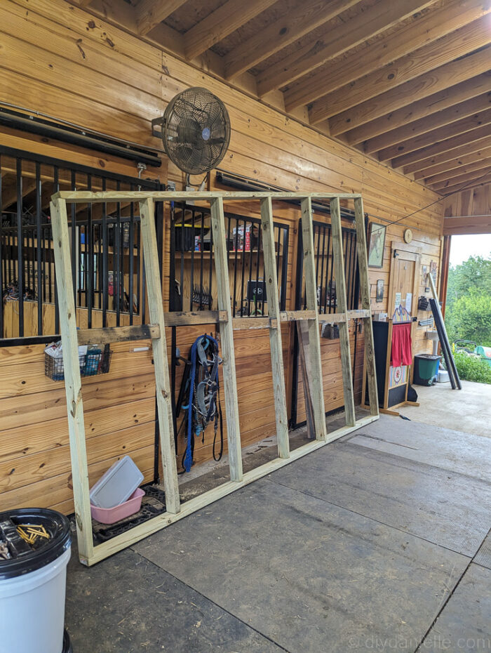 Front frame of a run-in shed for goats and sheep, built with pressure-treated 2x4s and open entry.