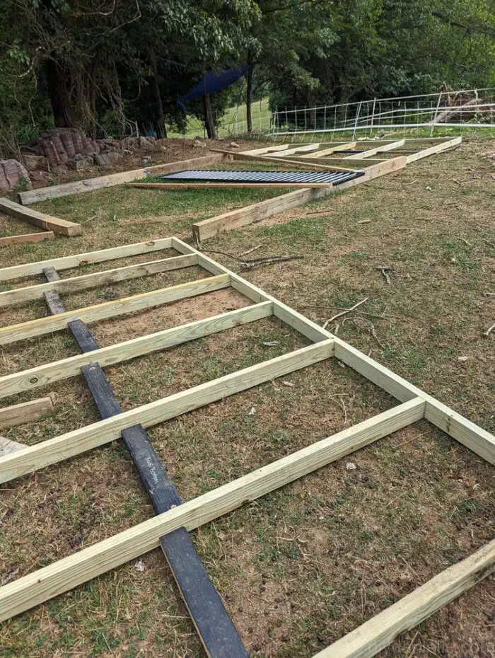 Base of a DIY livestock shed framed with thick 4x6 lumber on grassy ground.