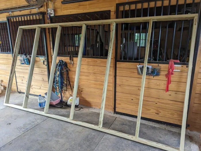 Wooden 2x4 frame of a run-in shed under construction, designed for goats and sheep.