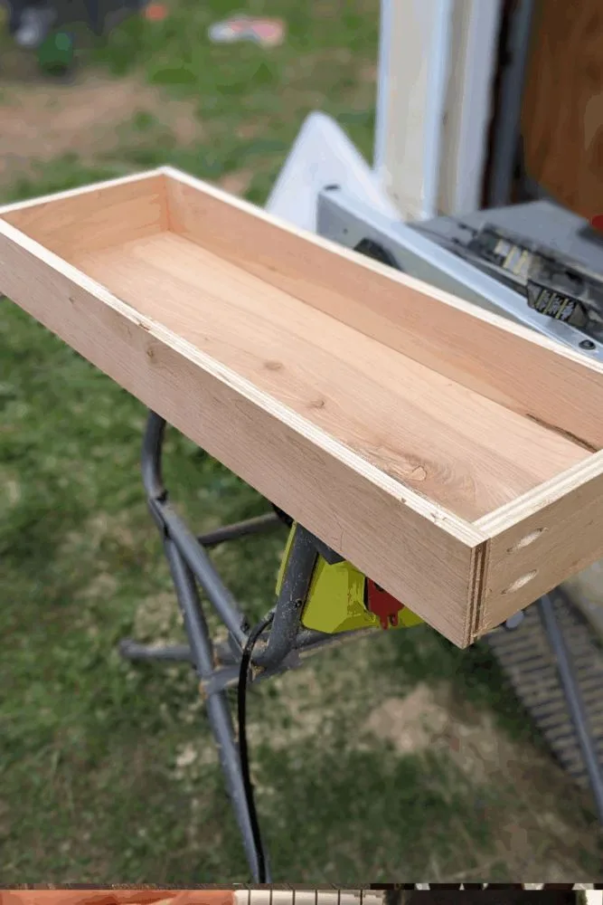 DIY drawer box with wood glue in grooves and 1/4" plywood bottom being slid into place before attaching the front panel.