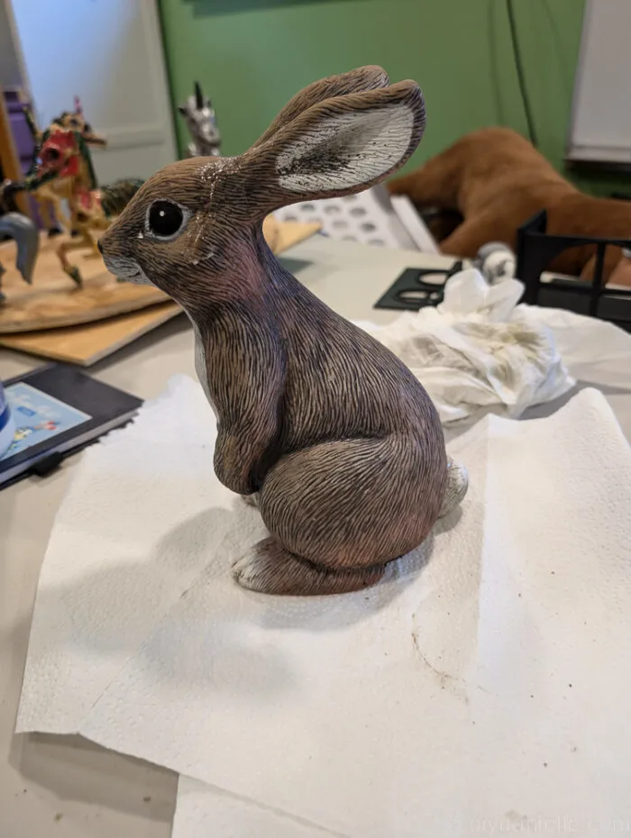 Garden rabbit statue transformed into a creepy zombie bunny with red eyes and painted details.