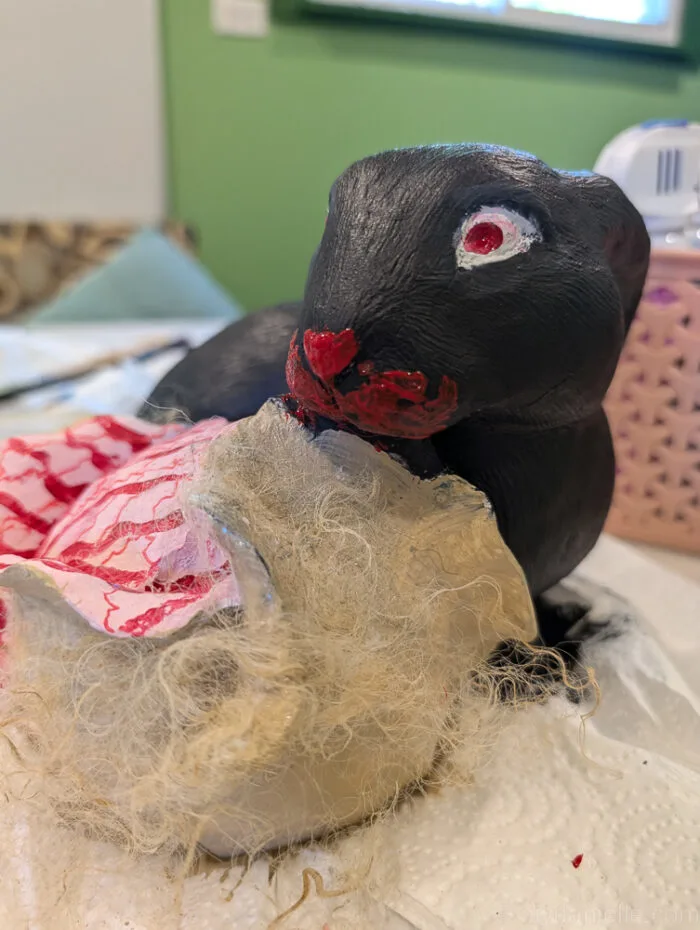 Finished zombie rabbit statue with glowing red eyes and distressed paint.
