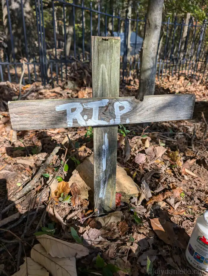 Handmade rustic grave cross made from old pallet wood with white painted “R.I.P.” letters.