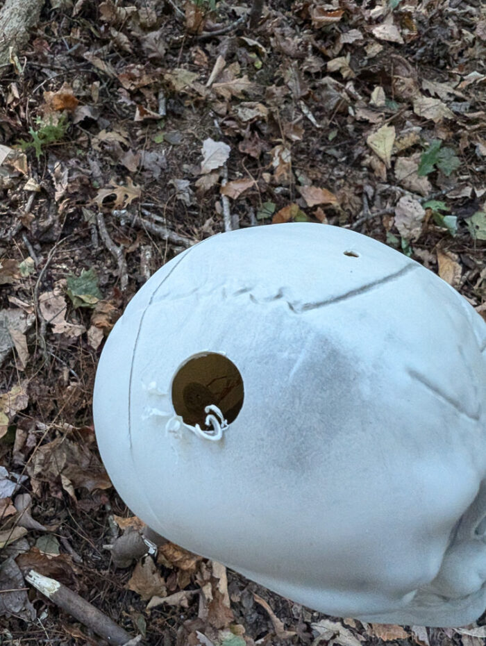 Close-up of drilled hole in the base of a plastic skull for inserting Halloween lights.