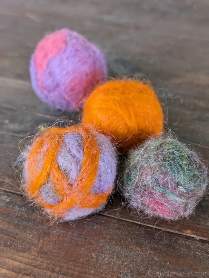 Needle felted catnip balls stored in a clear container for easy access
