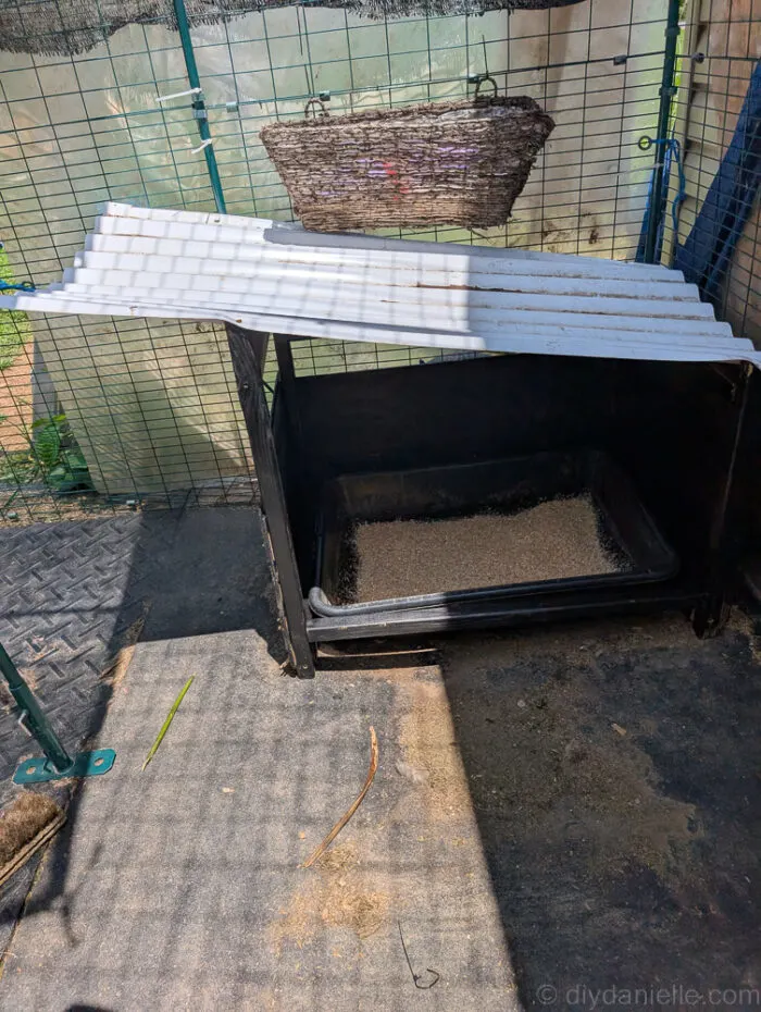 Painted outdoor litter box cover with lightweight roofing panel installed and litter box placed inside.