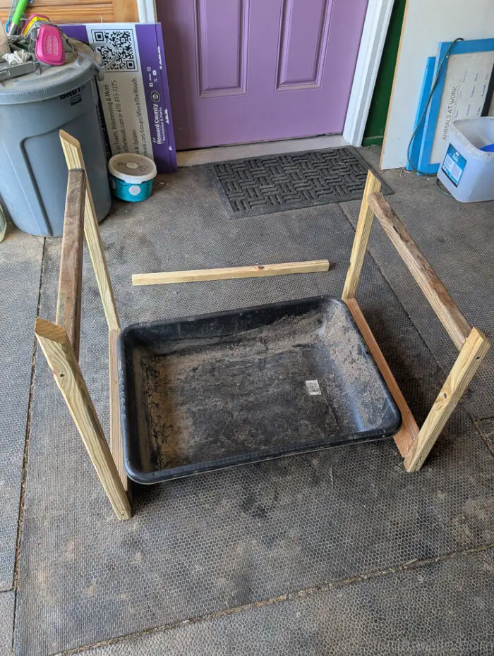 Litter box placed between two wooden frame pieces during construction of an outdoor cover.