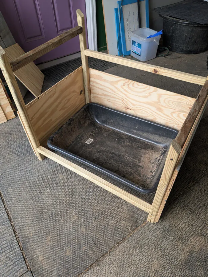 Opposite side view of a DIY outdoor litter box cover with angled roof and partial wood siding.