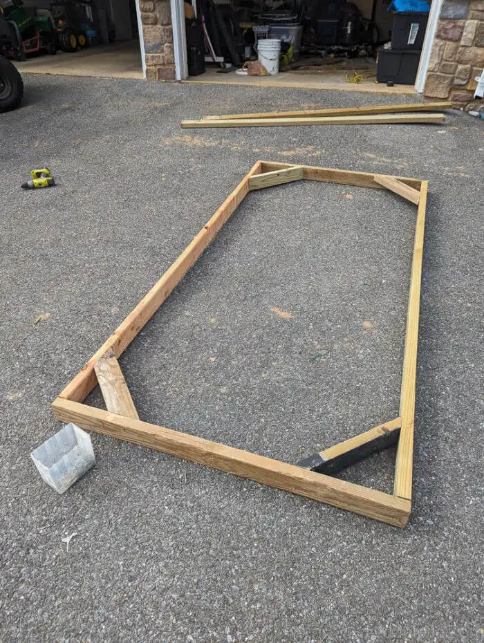 Close-up of diagonal wooden supports installed in the corners of a 2x4 privacy screen frame.