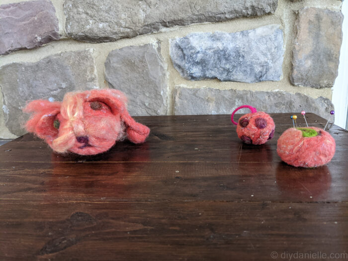 Handmade needle felted ball ornament with protruding wool pieces resembling a COVID model