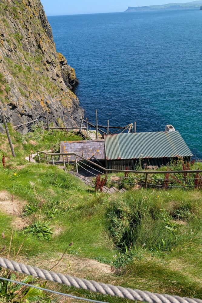 Small fisherman’s cabin perched on the cliffs at Carrick-a-Rede, Northern Ireland, surrounded by rocky coastline and ocean views