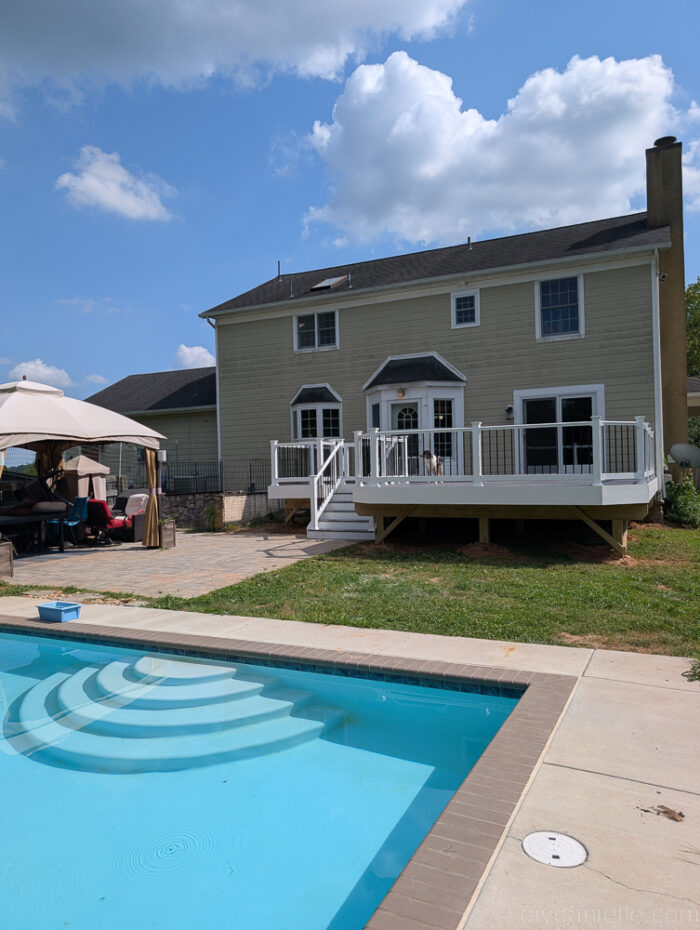 View of the deck and pool from the poolside showing the full backyard layout.