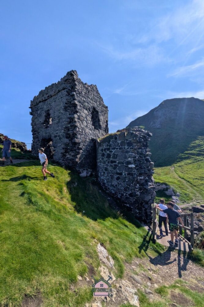 Children exploring the ruins of Kinbane Castle perched on cliffs with ocean views in Northern Ireland.