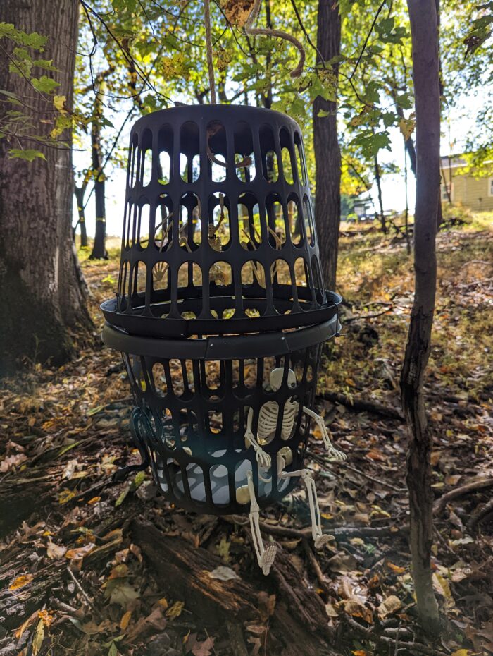 Large DIY Halloween cage containing a skeleton, set up as a spooky centerpiece for a prison or haunted house display.