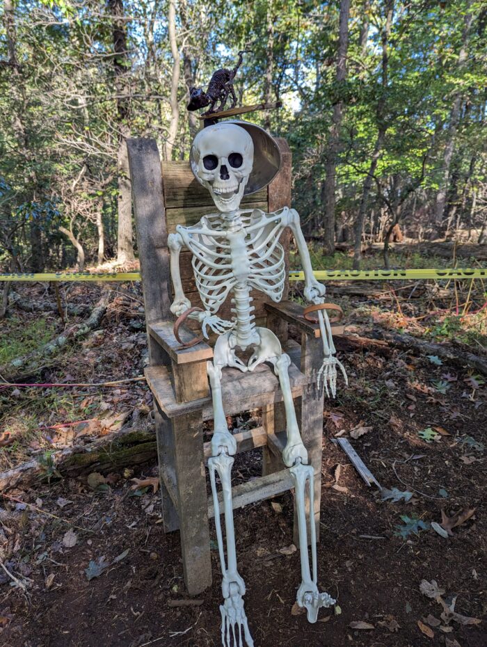 Skeleton sitting in a DIY electric chair, creating a spooky and dramatic Halloween prison-themed display.