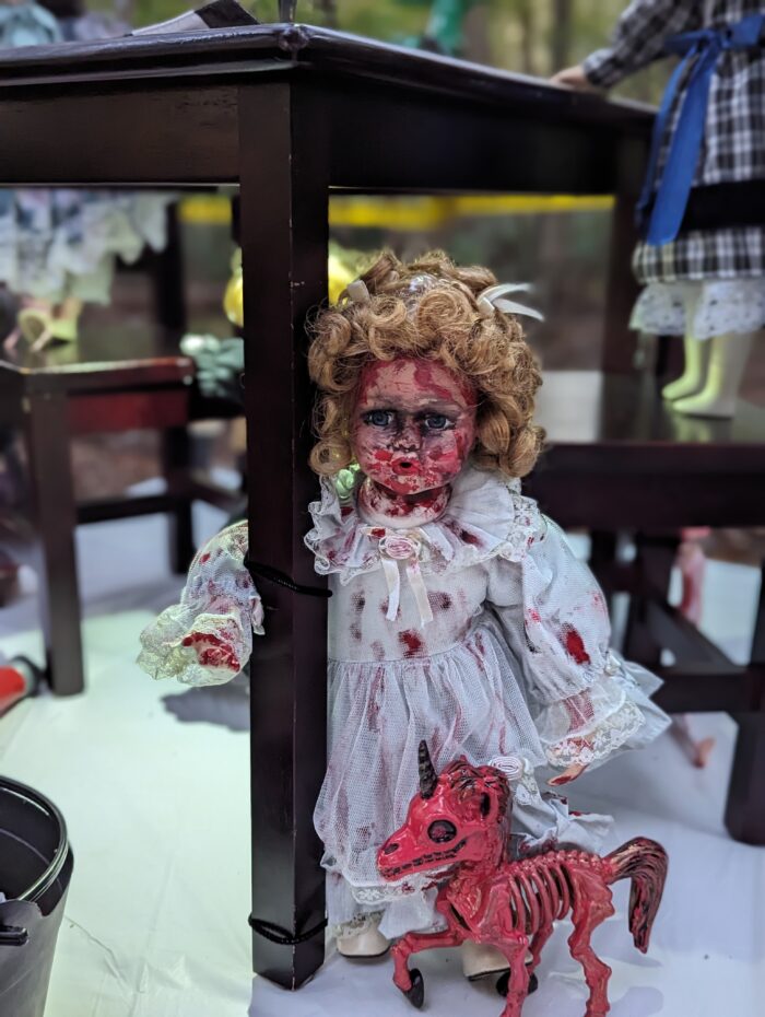 Doll in a white dress with a skeleton dog as part of the Halloween display.