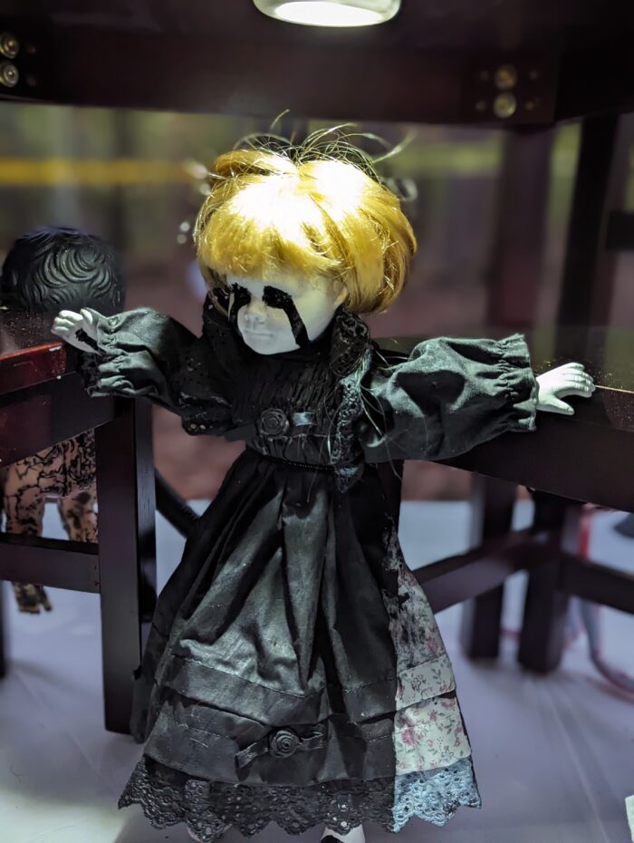 Creepy white doll in a black dress adding a spooky element to the scene.