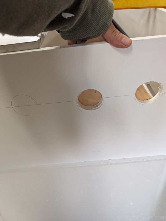Using a hole saw or spade bit to cut a correctly sized hole in a DIY ball python enclosure for ventilation or access.