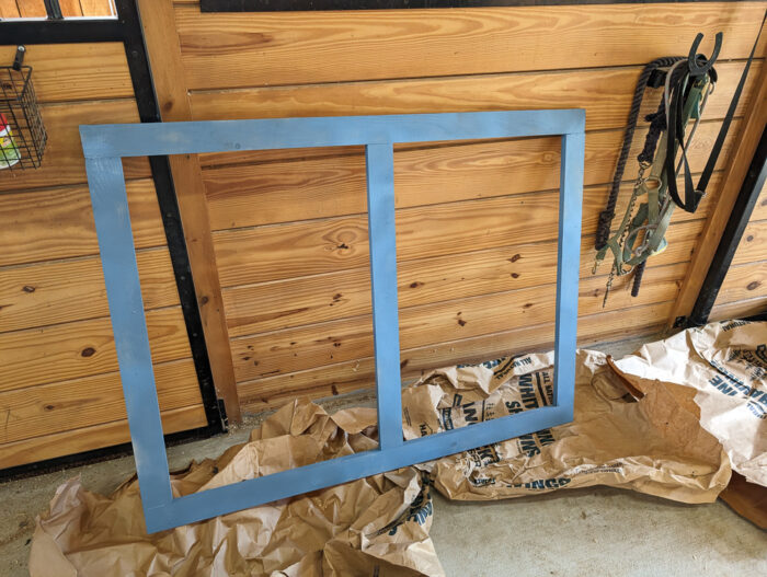 Wood frame attached to the front of a DIY ball python enclosure, painted to match the base with wheels, adding stability and a polished appearance.