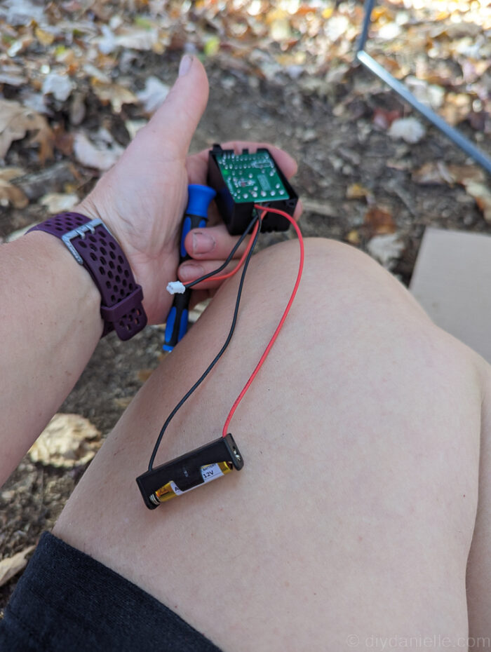 Close-up of wiring a relay transmitter for a DIY Halloween animatronic, showing the red wire attached to “in +” and the black wire attached to “in -.”