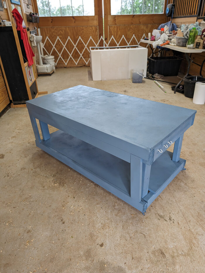 Close-up of a reptile enclosure stand showing a small hook attached for hanging feeding tongs or other reptile care tools.