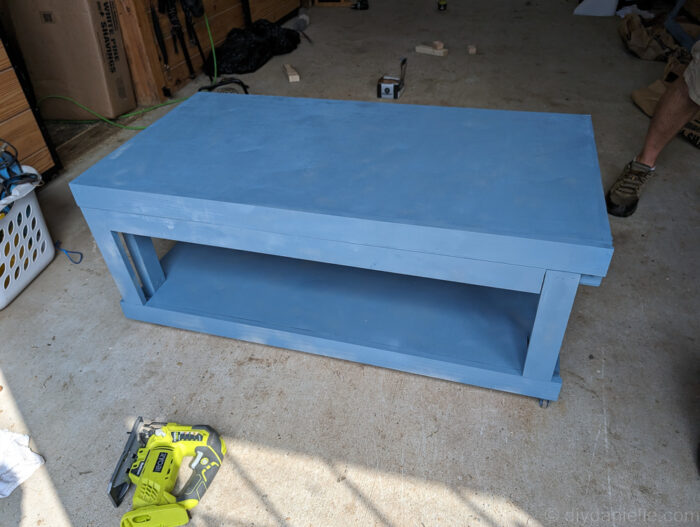Blue reptile enclosure stand built with 2x4 framing, showing a sturdy top and bottom shelf designed to support heavy tanks.