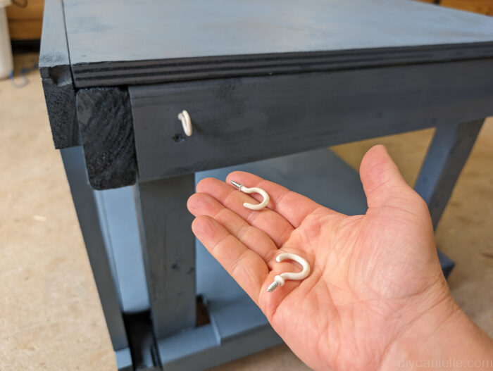 Reptile enclosure stand with a small hook attached on the side, perfect for hanging feeding tongs or other reptile care tools.