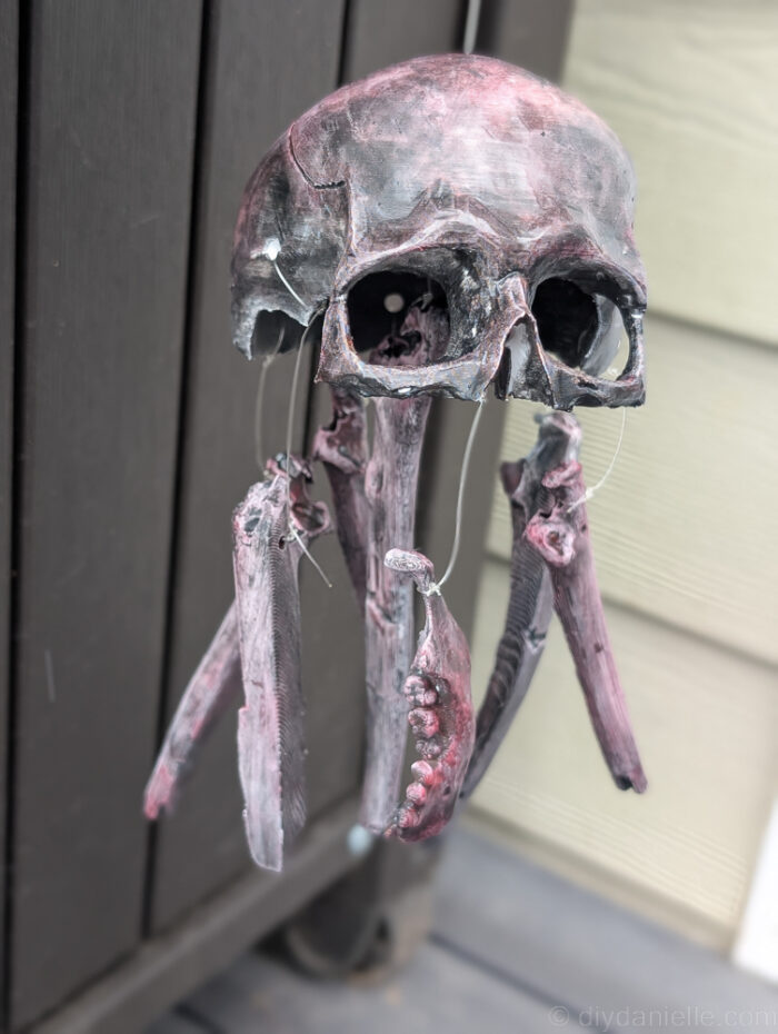 Handmade DIY skull baby mobile hanging above creepy dolls as a Halloween decoration.