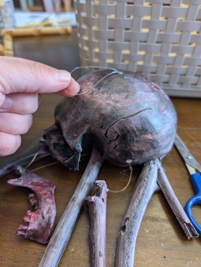 Close-up of DIY skull baby mobile with pieces tied together, showing a quirky, imperfect assembly for spooky décor.