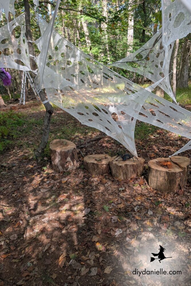 Fallen trees turned into a Halloween spider cavern using beef netting to create a webbed tunnel effect in the yard.