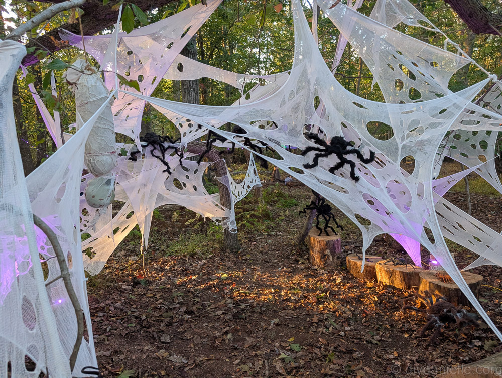 Hanging Halloween corpse suspended in webbing with three glowing purple spider egg sacs nearby.