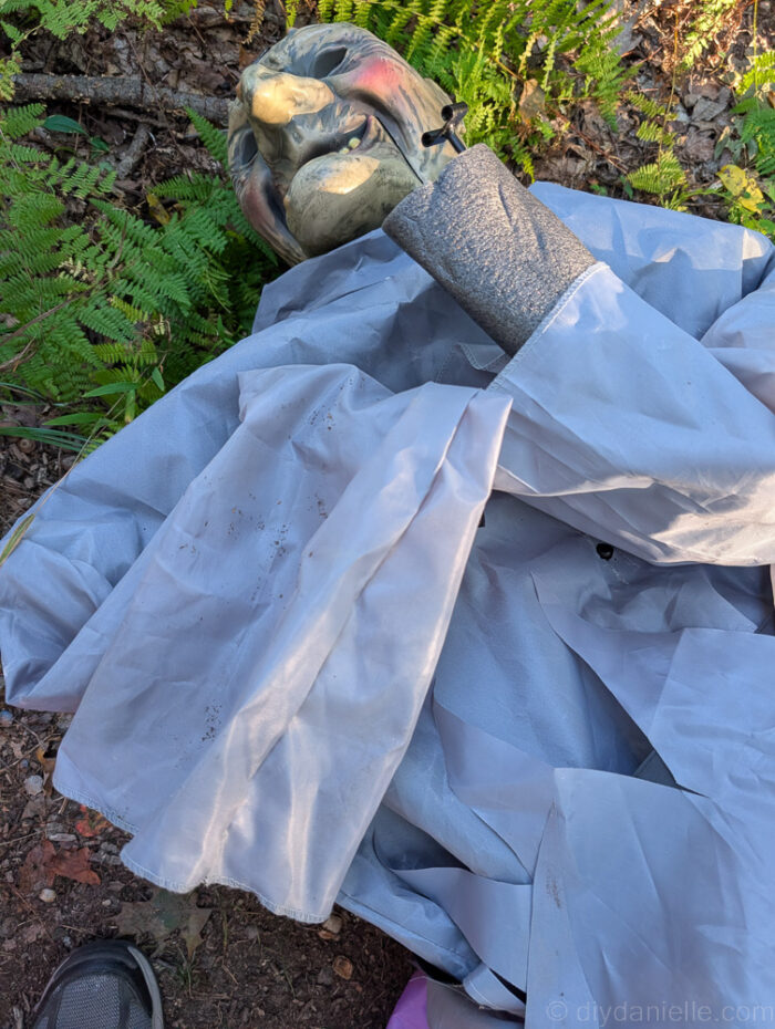 Metal support bar with attached white box being installed on a 12 ft. Hovering Witch Halloween decoration for stability.
