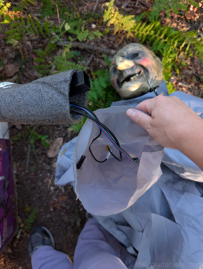 Close-up of attaching the witch’s arm and sliding her sleeve over the support during setup of a 12 ft. Hovering Witch Halloween decoration.