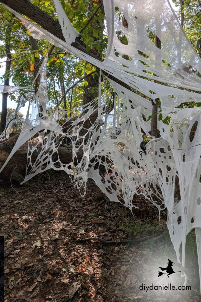 Close-up of beef netting wrapped between fallen tree limbs to form a spider cavern for Halloween décor.