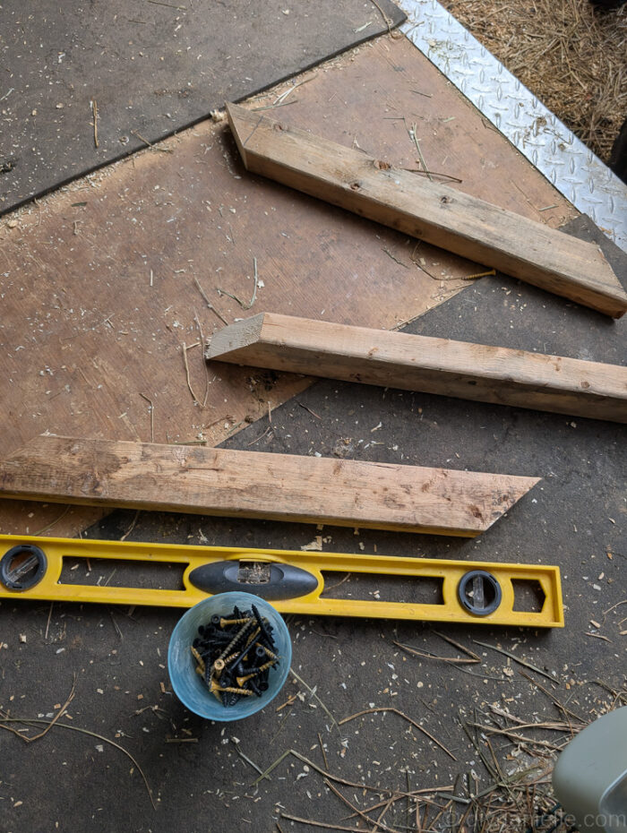 Cutting 2x2 wood boards at 45-degree angles with a miter saw for a wall mounted hay feeder project.