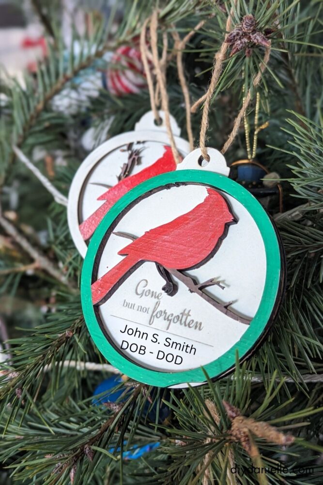 Two-layered cardinal ornament with a white-painted base, engraved text, and custom details for a memorial keepsake.