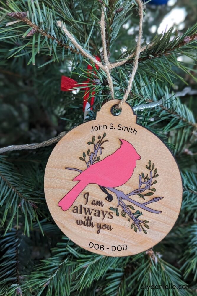Engraved and hand-colored cardinal ornament with personalized name and dates, showcasing a detailed DIY design.