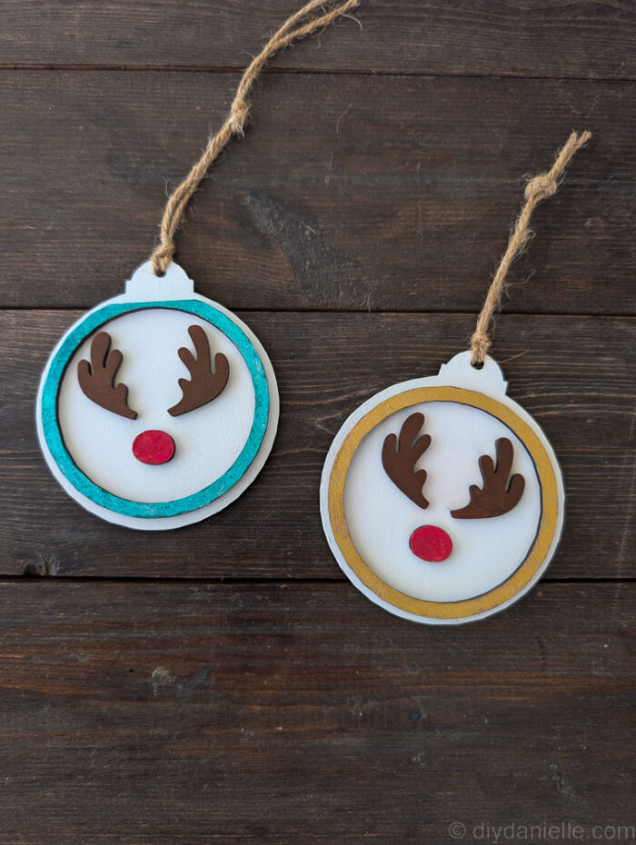 Several completed two-layer wooden Christmas ornaments in various colors, showing different color combinations and finishes.