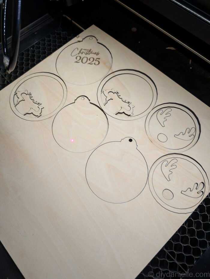 Two-layered DIY Christmas ornament pieces being glued together after laser cutting, ready for painting and customization.