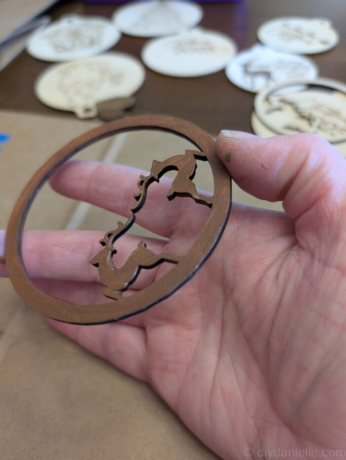 Separate layers of a wooden Christmas ornament being painted individually for a neat, professional-looking finish.