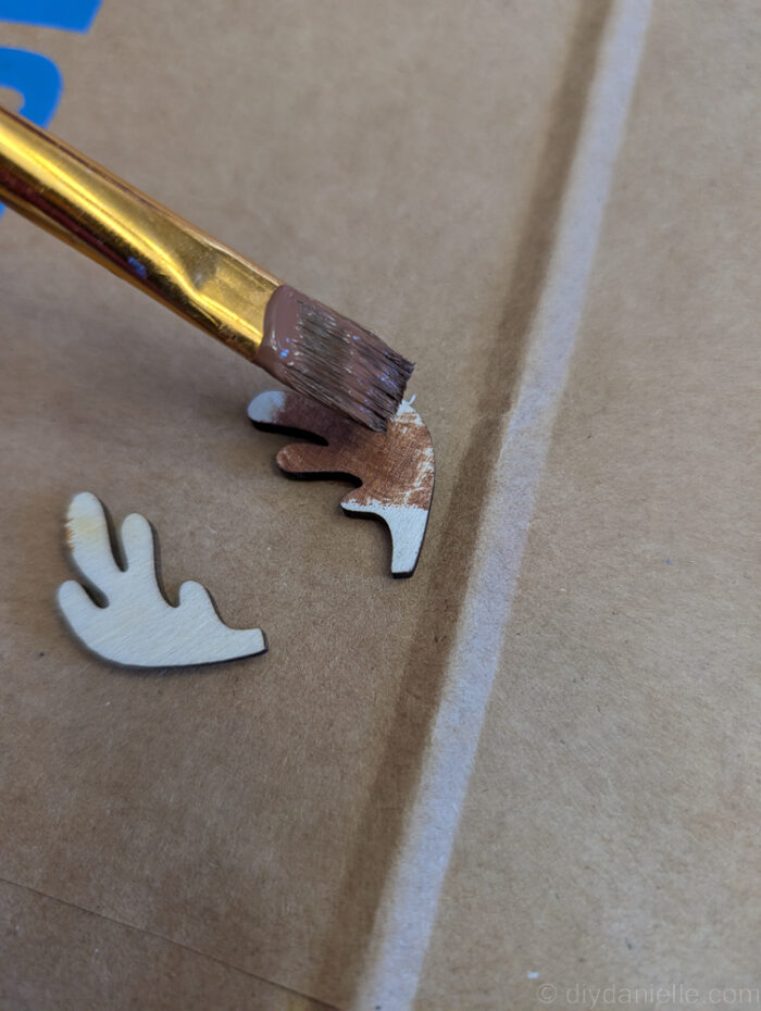 Separate layers of a wooden Christmas ornament being painted individually for a neat, professional-looking finish.