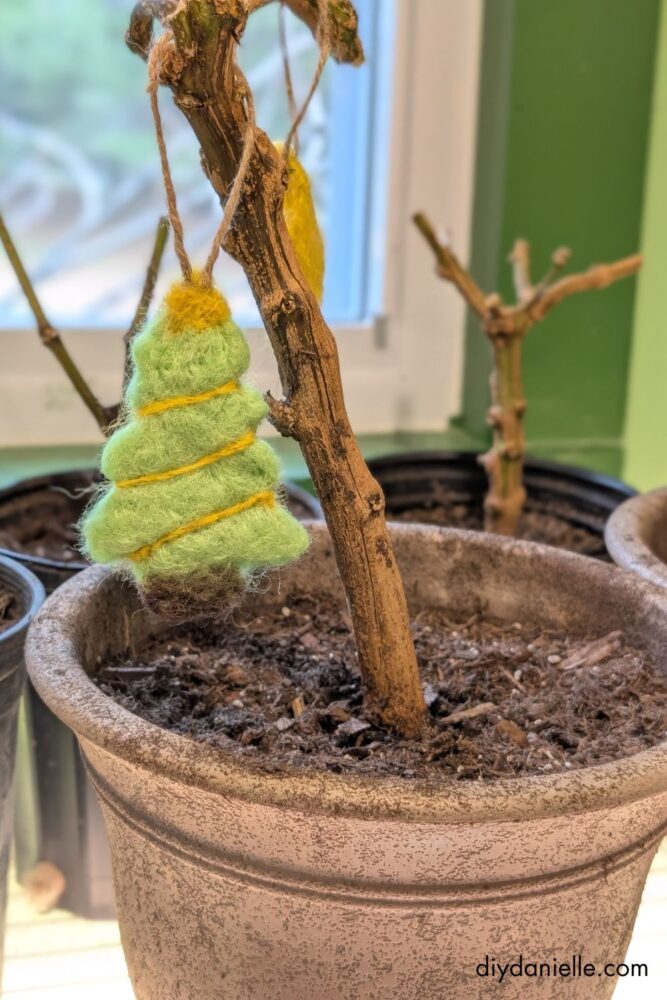 Close-up of hands using scissors to trim loose fibers from a felted wool ornament for a neat and polished finish.
