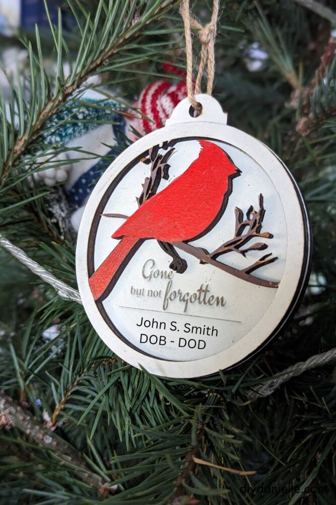 Two-layered cardinal ornament with a white-painted base, engraved text, and custom details for a memorial keepsake.