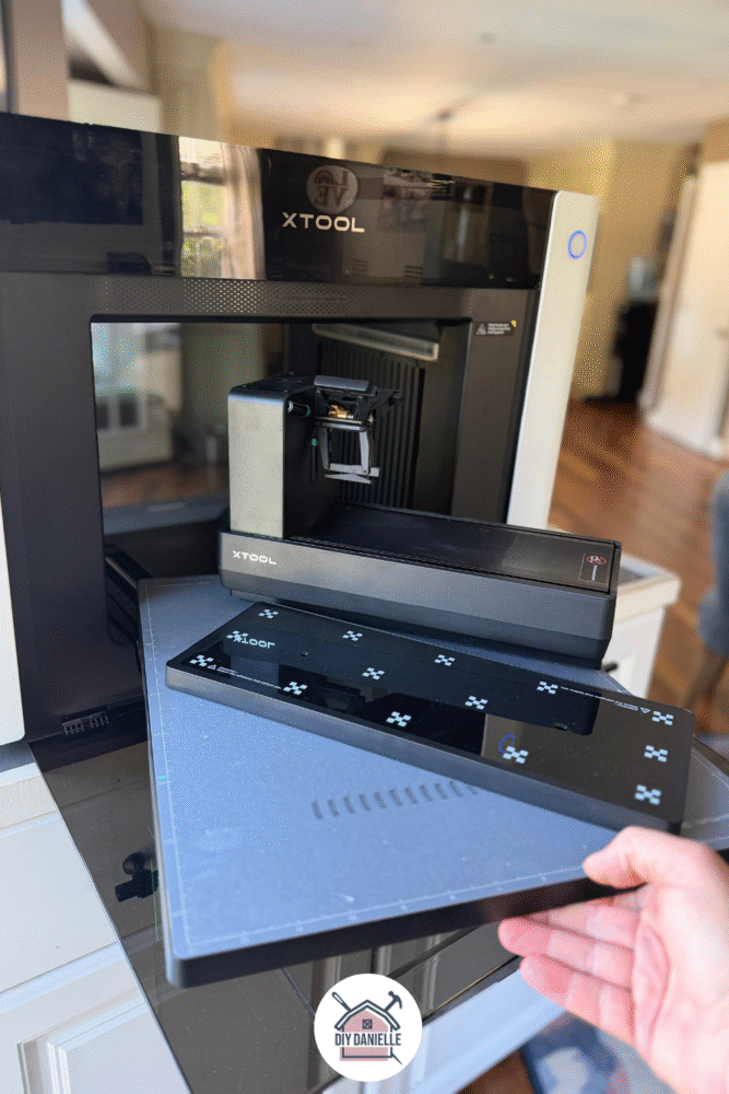 Photo of the O1 Dual Head Omni UV printer on a large rolling stand. The front is open. The small plate, the larger plate and the rotary plate are stacked on top of each other.